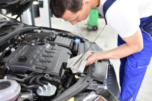 Mechaniker kontrolliert lstand vom Motor eines autos in der Werkstatt // professionel oil check from the engine of a car in repair shop